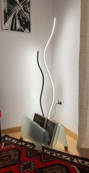 A modern room with a unique light sculpture, a patterned rug, and a framed picture on the wall. - Cozy apartment for families and couples, proximity to Cansiglio Golf Club. (Osigo)