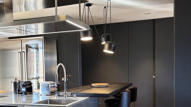 A modern kitchen with stainless steel appliances, a central island, bar stools, and pendant lighting. - Exclusive penthouse in the historic center of Alba, panoramic terrace with garden and private  pool and solarium. (alba)