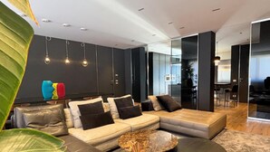A modern living room with a sectional sofa, a coffee table, and a large plant. - Exclusive penthouse in the historic center of Alba, panoramic terrace with garden and private  pool and solarium. (alba)