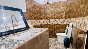 A bathroom with a marble sink, a bathtub, and a toilet.