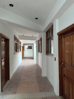 Un pasillo con piso estampado, puertas de madera y paredes blancas.