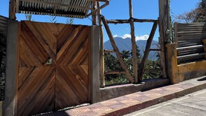 A gated entrance with a corrugated metal roof, a wooden gate, and a sign indicating a rental property with wifi and kitchen amenities.