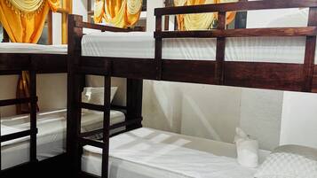 Dormitorio con literas de madera, ropa de cama blanca y cortinas amarillas.