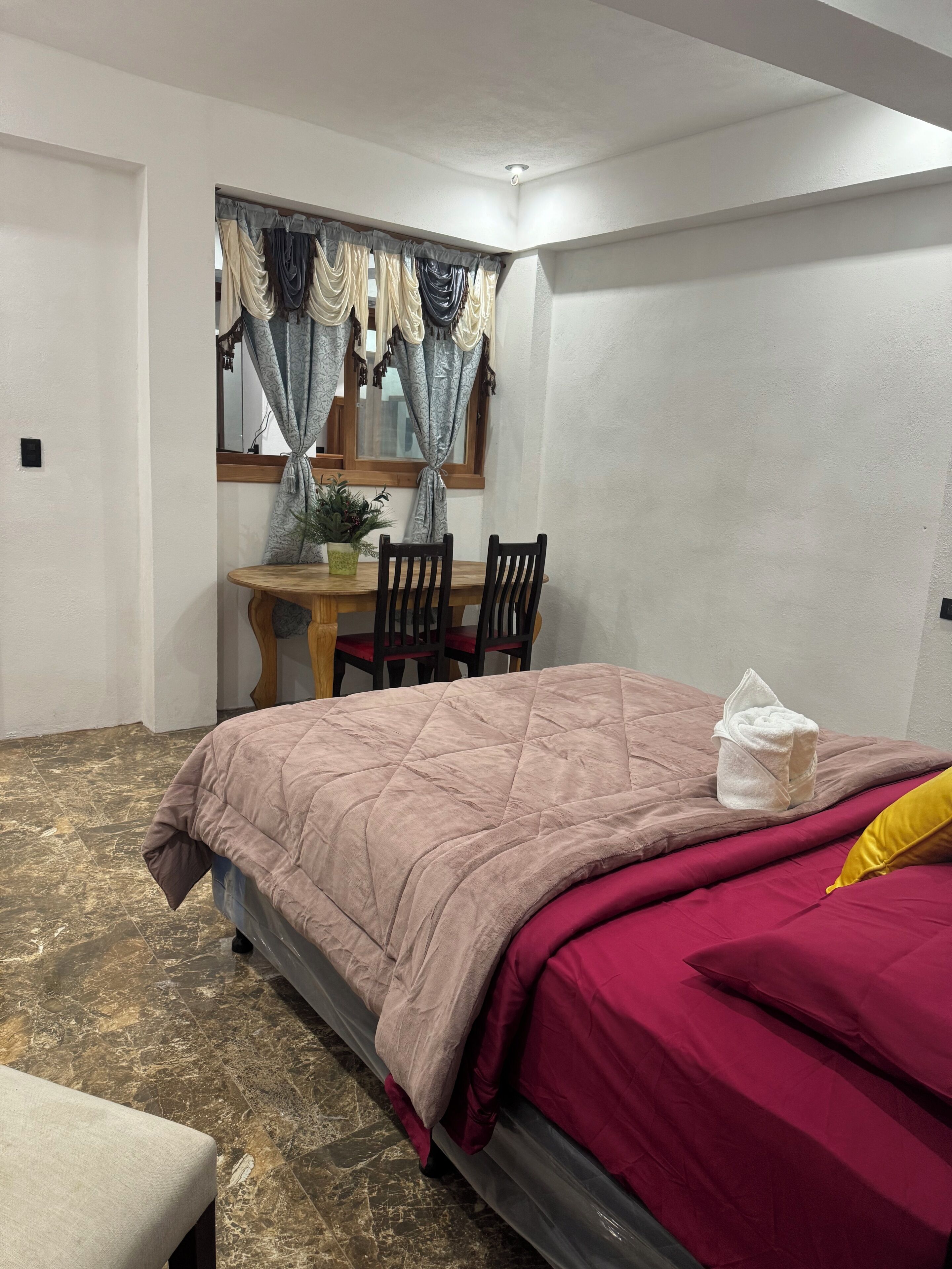Un dormitorio con cama, escritorio y sillas.