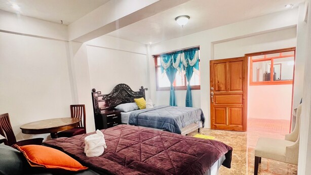A bedroom with two beds, a wooden wardrobe, a small table, and a chair.