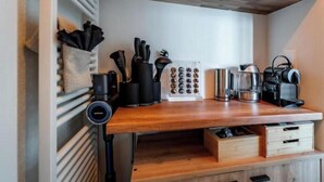 Et køkken med en træbordplade, kaffemaskine, elkedel og et knivstativ.