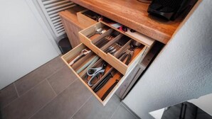Een keuken met een houten aanrecht, een koffiezetapparaat en een lade met keukengerei.