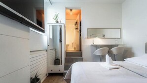 Et moderne hotelværelse med seng, skrivebord, stol, spejl og en trappe til et badeværelse.