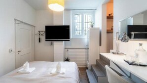 Een hotelkamer met een bed, een bureau, een televisie en een raam met uitzicht.
