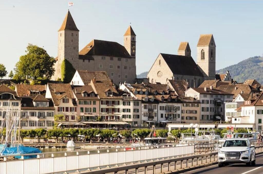 A historic building with multiple towers and a river in the foreground.