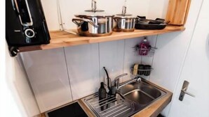 Een kleine keuken met een ingebouwde kookplaat, een spoelbak en een houten aanrecht.