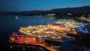 Un puerto deportivo con varias embarcaciones amarradas, un muelle que se adentra en el agua y un paisaje urbano al fondo.