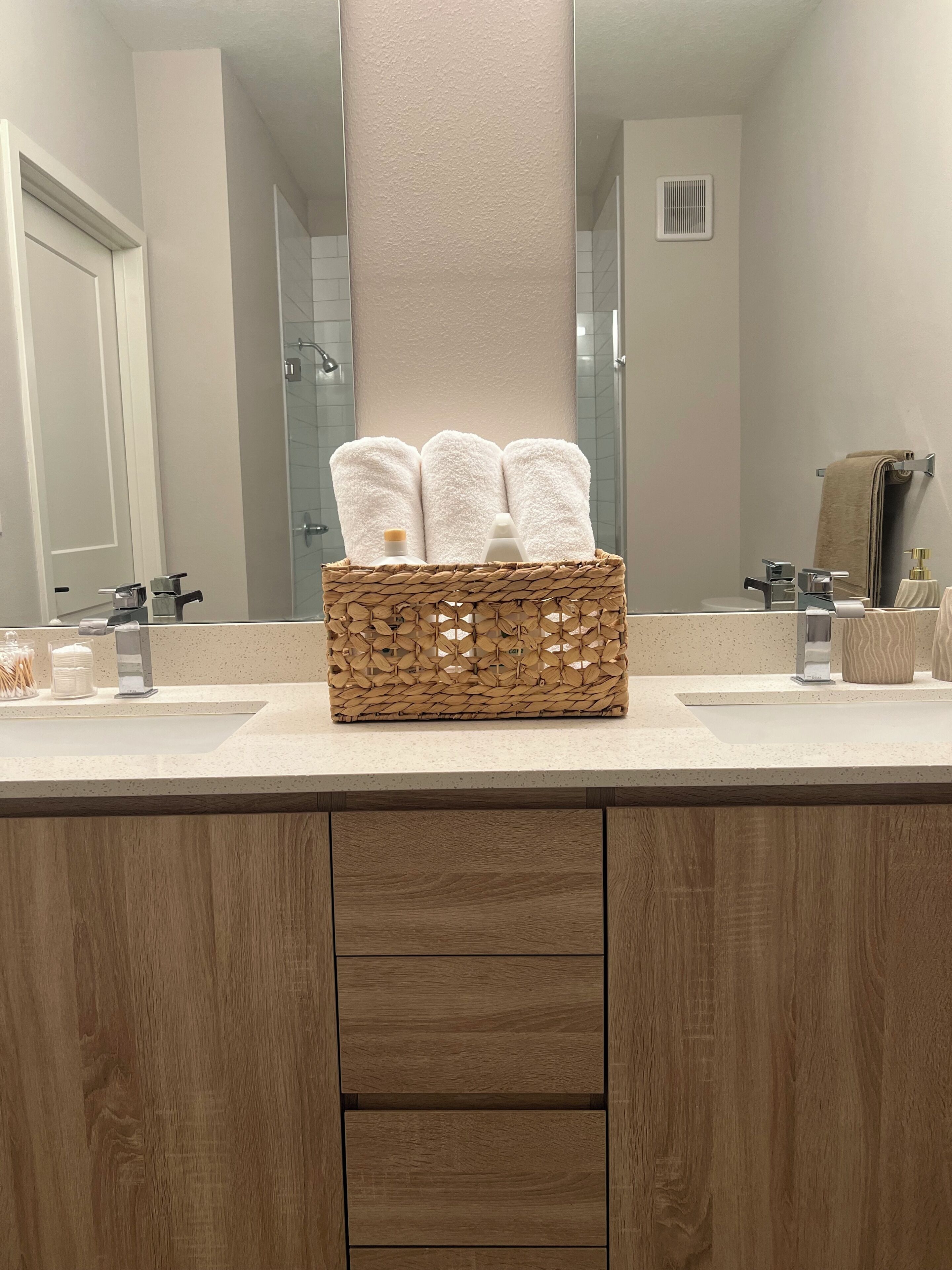 A bathroom with two sinks, a mirror, a towel rack, and a wooden cabinet.