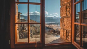 A view through a window with a stone wall and a metal gate, leading to a mountainous landscape. - La Grange de la Petite Ourse with Large Furnished Terrace, Stunning Lake and Mountain Views (Les Angles)