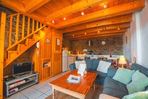 En hyggelig stue med en trætrappe, en sofa, et sofabord og et fjernsyn.