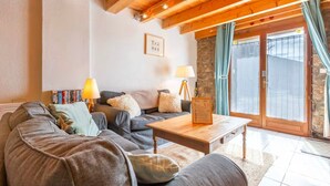 A cozy living room with a sofa, two lamps, a coffee table, and a stone wall. - La Grange de la Petite Ourse with Large Furnished Terrace, Stunning Lake and Mountain Views (Les Angles)