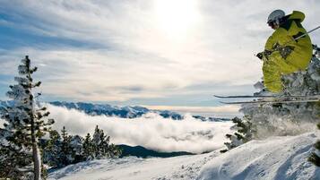 Eine verschneite Berglandschaft mit einem Skifahrer in gelber Ausrüstung.