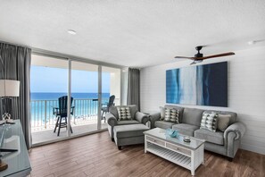 A living room with a balcony, a ceiling fan, and a large abstract painting.