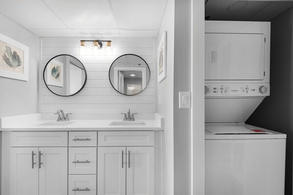 A modern bathroom with two sinks, a mirror, and a built-in washing machine. - Long Beach Tower 1-605 1-Bedroom Condo With Seasonal Beach Chairs with Umbrella (Panama City Beach)