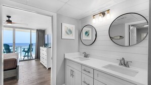 Een moderne badkamer met een grote spiegel, twee wastafels en een plafondventilator.