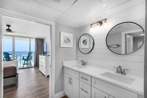 Une salle de bain moderne avec un grand miroir, deux lavabos et un ventilateur de plafond.