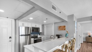Een moderne keuken met witte kasten, roestvrijstalen apparatuur en een centraal eiland met barstoelen.