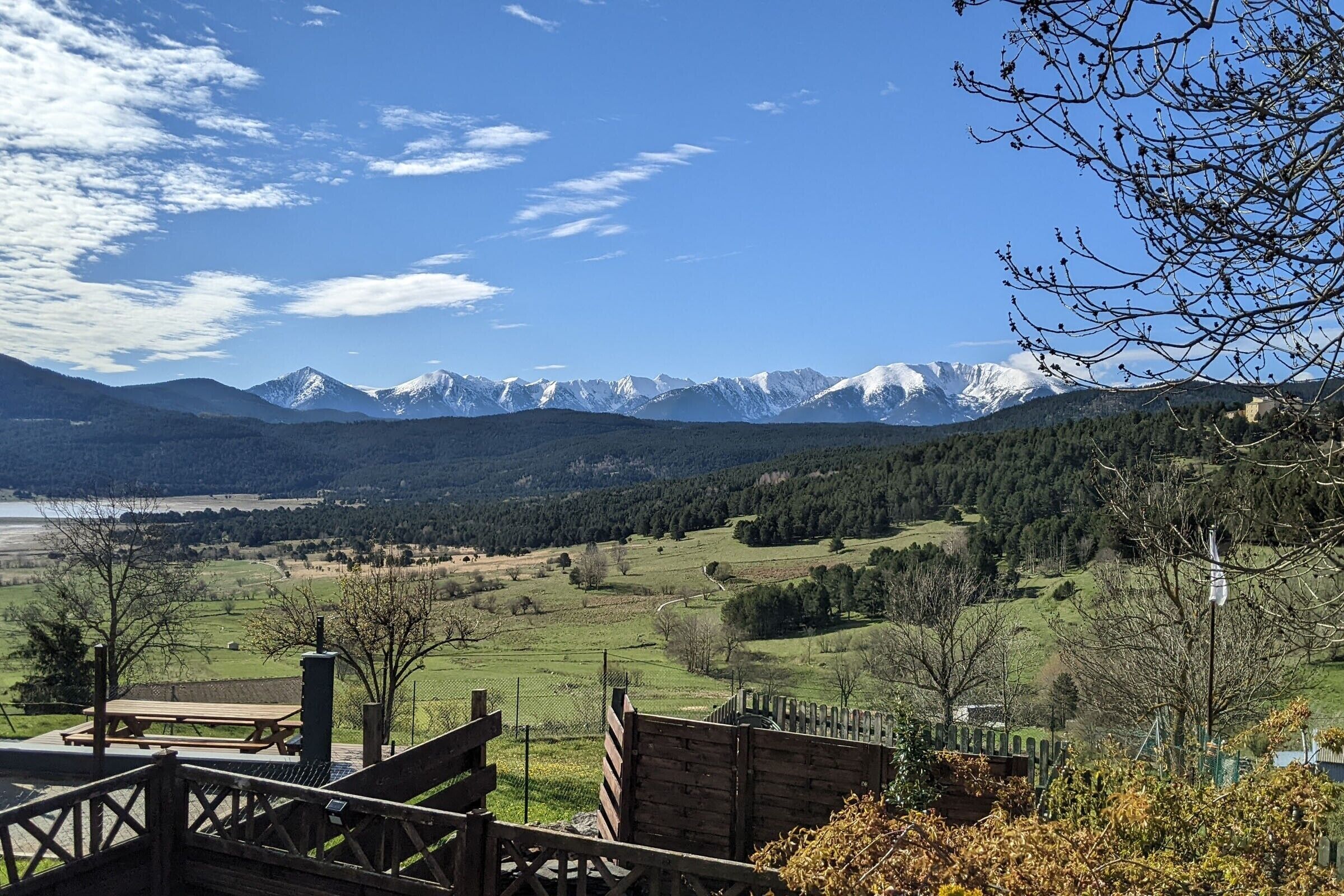A scenic view of a mountainous landscape with a wooden deck and picnic table.