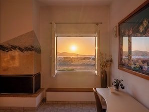 Ein Zimmer mit Blick auf den Sonnenuntergang, einem Kamin, einer Bank und einem Wandbild.