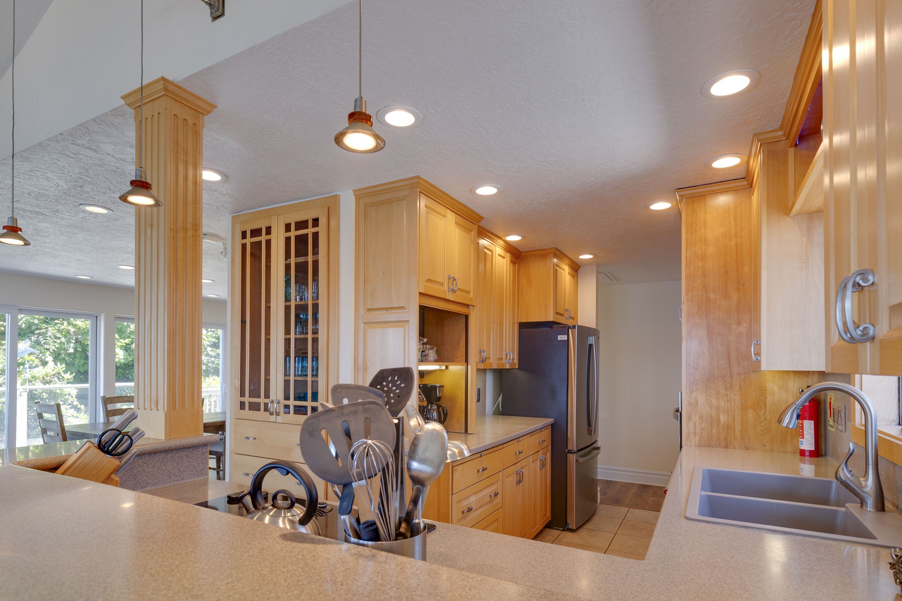A modern kitchen with wooden cabinets, stainless steel appliances, and pendant lighting.