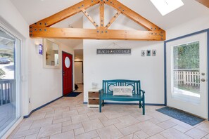 A hallway with a wooden ceiling, a red door, a bench, and a sign that reads 'BEACH COTTAGE'. - Pelican's Perch at Neskowin Ocean View (Cloverdale)