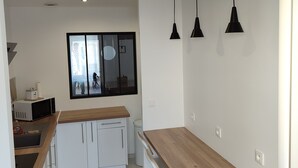 Et moderne køkken med hvide skabe, en træbordplade og hængende sorte lamper.
