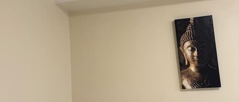Une chambre à coucher avec un lit, une table de chevet dotée d’une lampe et d’une horloge numérique, et un tableau accroché au mur.