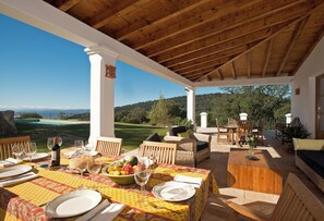 An outdoor dining area with a view of a golf course, wooden furniture, and a table set for a meal. - All About Rif View Villa (Málaga)