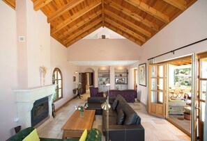 A spacious living area with a fireplace, a sofa, a coffee table, and a dining area with chairs. - All About Rif View Villa (Málaga)