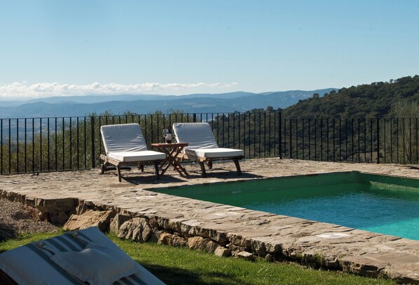 A pool with lounge chairs and a table, surrounded by a stone deck and a metal fence, overlooking a mountainous landscape. - All About Rif View Villa (Málaga)