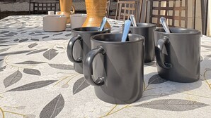 A courtyard with a tiled roof, stone walls, and a table with black mugs and a woven basket. - Charming, quiet house - heated pool-5 minutes from pretty village of Eygalières (Orgon)