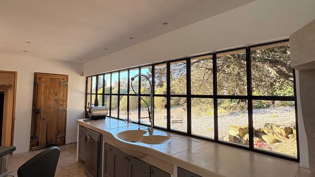 A modern kitchen with a large window, a sink, and a chair. - Charming, quiet house - heated pool-5 minutes from pretty village of Eygalières (Orgon)