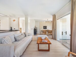 Ein modernes Wohnzimmer mit einer Couch, einem Holztisch und einem Essbereich mit Tisch und Stühlen.