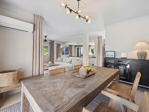 Ein geräumiger Wohnbereich mit einem großen Esstisch aus Holz, einer Couch und einer Küche im Hintergrund.