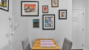 A room with a wooden table, two chairs, and various framed artworks on the wall. - The Little Erko A Gateway to Sydneys Indie Heart (Newtown)