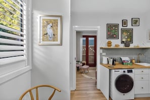 Cocina compacta con lavadora, un pequeño comedor y un pasillo que conduce a una puerta.