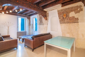A room with exposed wooden beams, a sofa, a table, and a decorative wall. - [Desiderium Home] A stone's throw from the Arena, Juliet's House, Roman Theater (Verona)