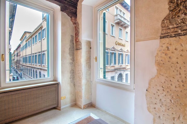 A room with large windows, exposed brick walls, and a radiator. - [Desiderium Home] A stone's throw from the Arena, Juliet's House, Roman Theater (Verona)