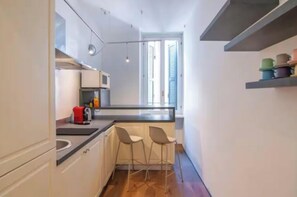A narrow kitchen with a window, a coffee machine, and two bar stools. - [Desiderium Home] A stone's throw from the Arena, Juliet's House, Roman Theater (Verona)