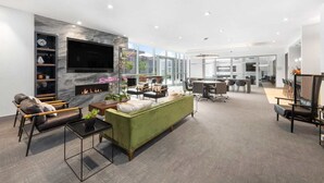 A modern living room with a fireplace, a sofa, a TV, and a dining area with a table and chairs. - Downtown Stamford Luxury | Indoor Pool & Gym (Stamford, CT)