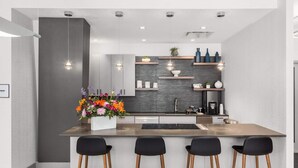 A modern kitchen with a central island, bar stools, and a decorative flower arrangement. - Downtown Stamford Luxury | Indoor Pool & Gym (Stamford, CT)
