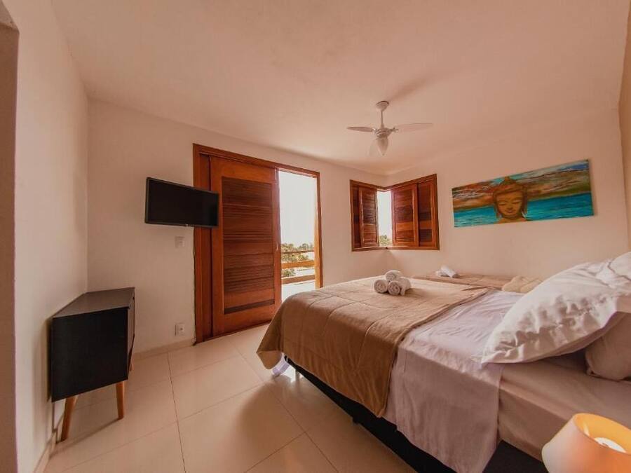 Ein Schlafzimmer mit einem Bett, einem Fernseher, einem Deckenventilator, einem Gemälde und Blick durch eine Tür.