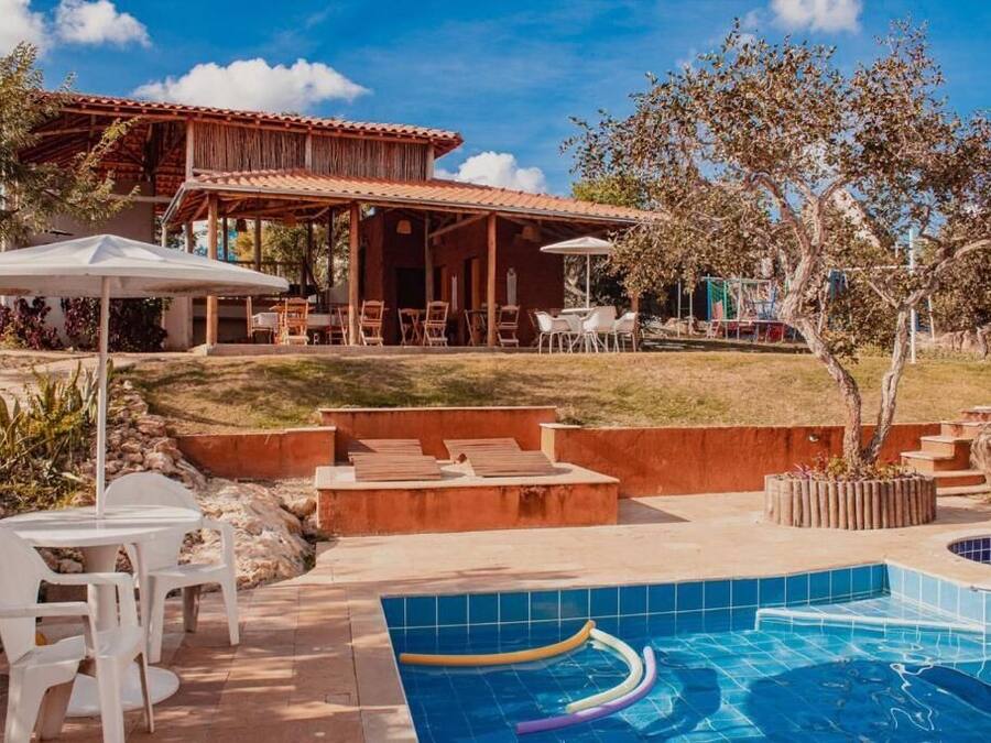 Un espace piscine avec des chaises longues, un patio couvert et un bâtiment doté d’un toit en tuiles.