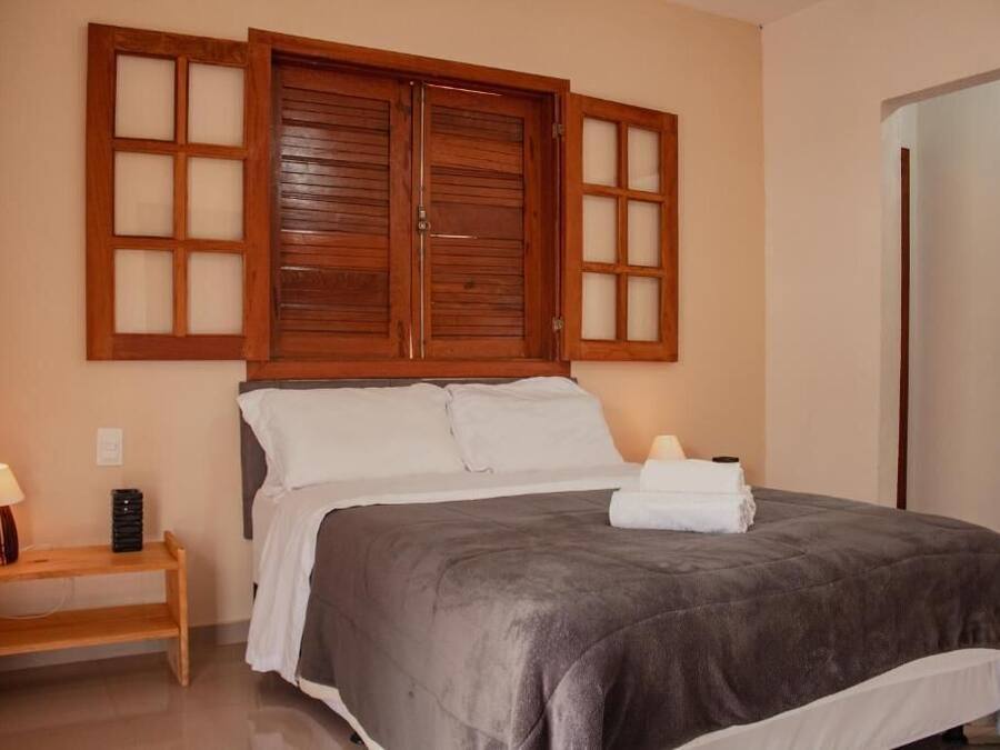 Un dormitorio con una cama grande, cabecera de madera, lámparas de noche y una mesita de noche.