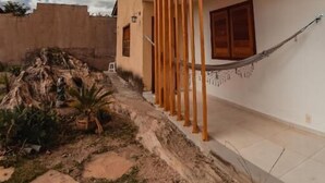 A two-story house with a balcony, a wooden fence, and a garden with a tree and a potted plant. - Soham Guest House (Diamantina)